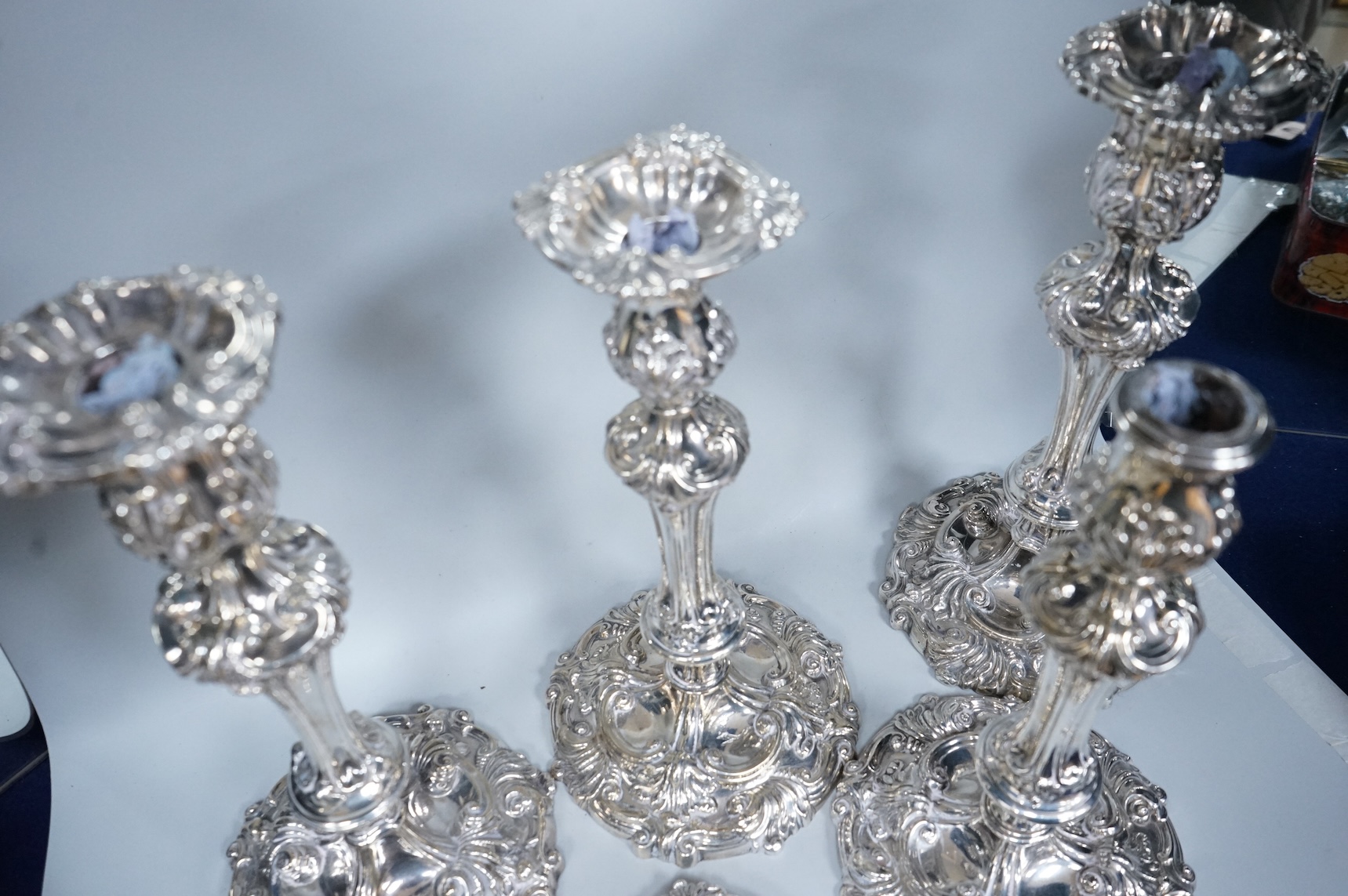 Two similar pairs of George III silver candlesticks, both with fluted tapered columns and decorated with foliage and scrolls, fixed sconces, makers mark rubbed, Sheffield, 1814 and S.C. Younge & Co, Sheffield, 1816, 28.5